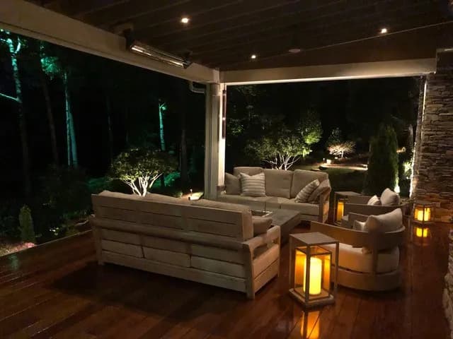 Cozy outdoor seating area with lanterns, illuminated trees, and a serene nighttime ambiance.