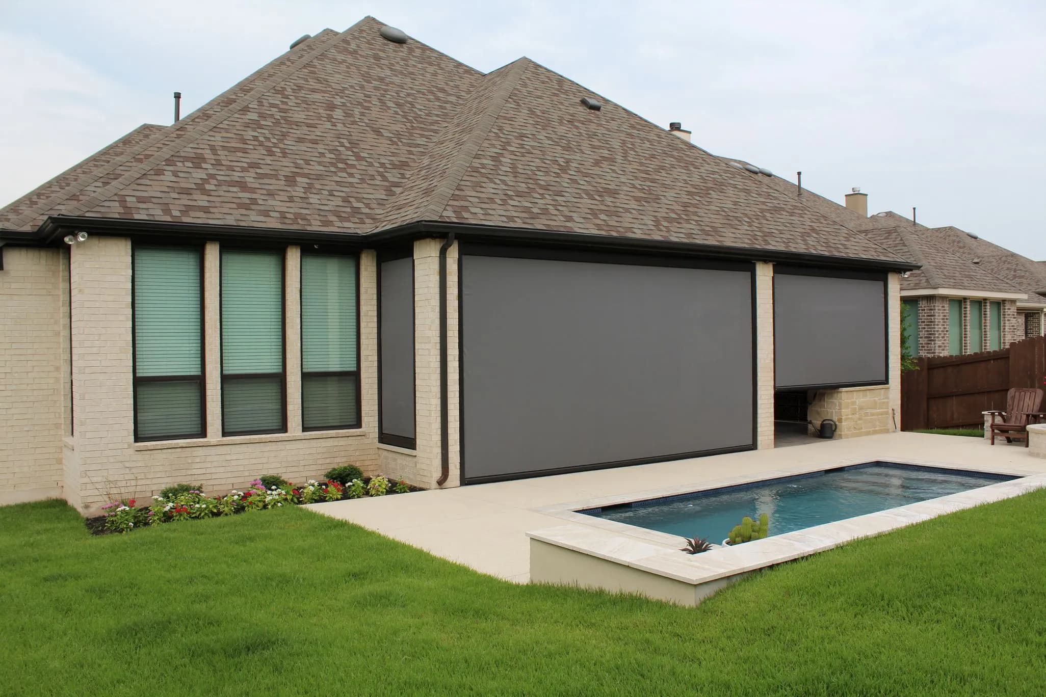 Modern home exterior with retractable screens, swimming pool, and landscaped yard.