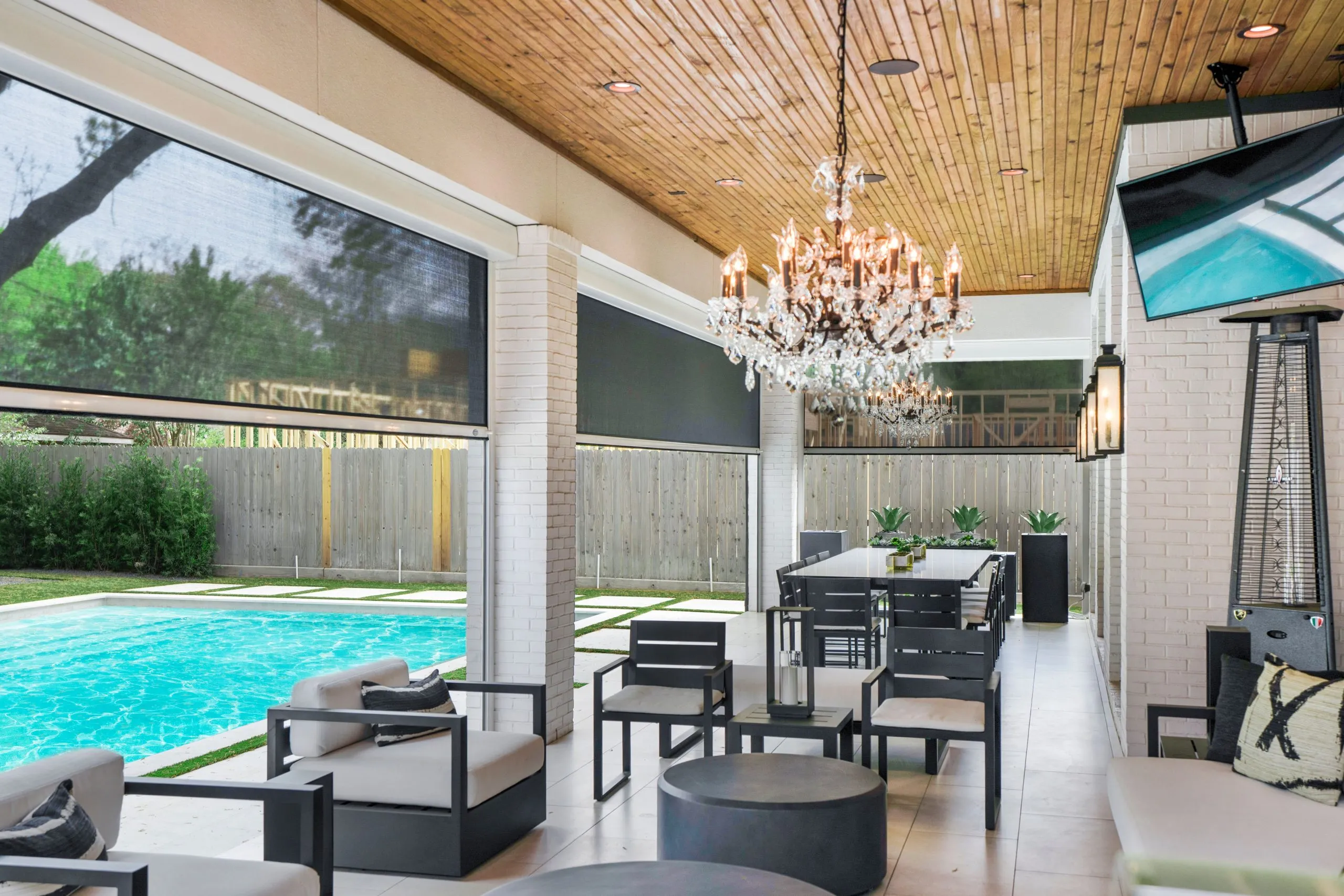 Modern outdoor living space with pool, elegant chandelier, and stylish seating area.
