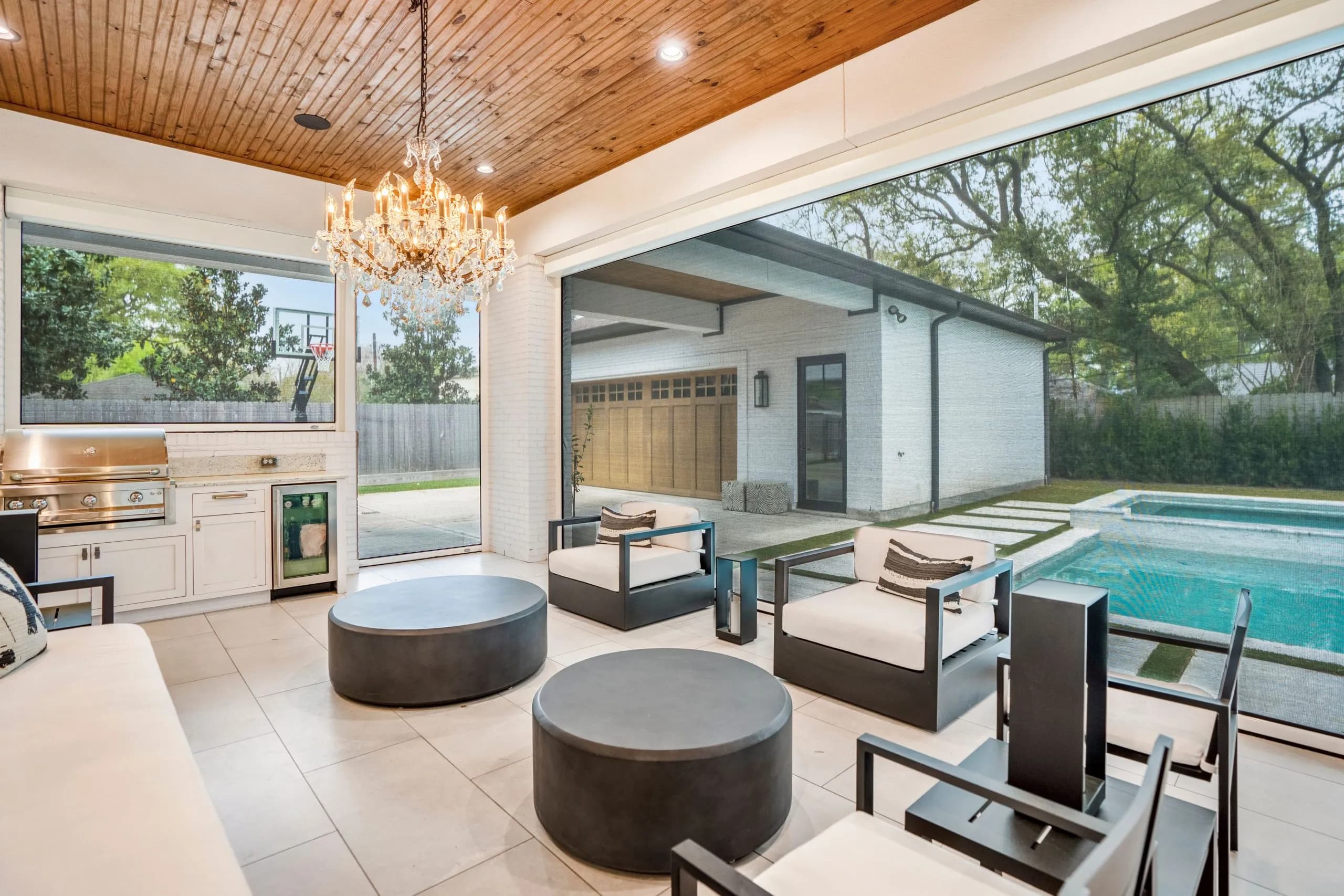 Elegant outdoor lounge with a pool view, modern furniture, and gourmet outdoor kitchen.