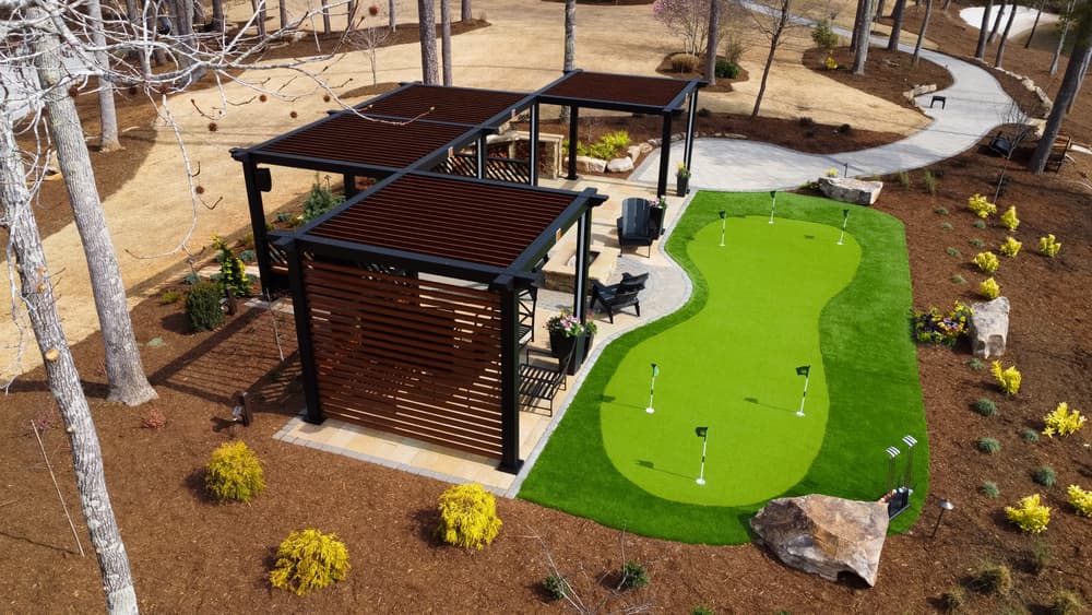 Lush backyard putting green with modern pergola and landscaped garden features.