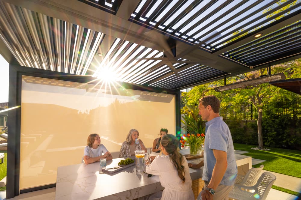 Group enjoying time together under a modern outdoor patio with sunlight and greenery.